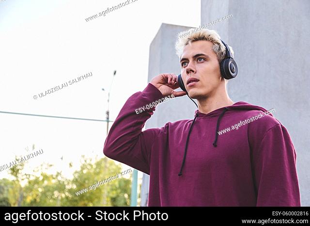 Young sports man in hoodie with headphones on work out area
