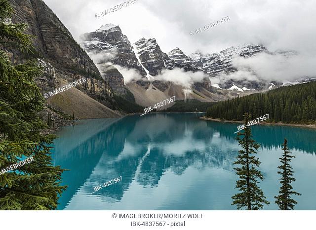 Clouds hanging between the mountain peaks, reflection in turquoise glacial lake, Moraine Lake, Valley of the Ten Peaks, Rocky Mountains, Banff National Park