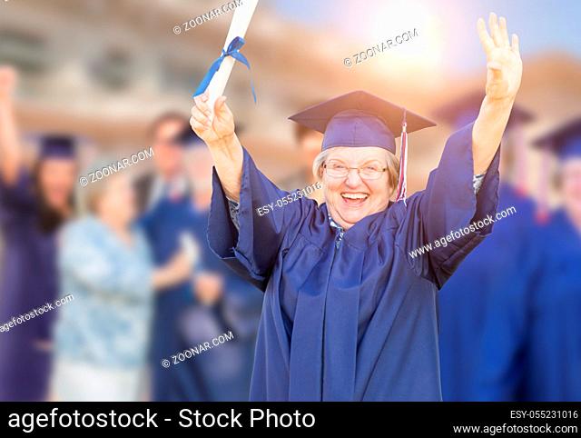 Happy Senior Adult Woman In Cap and Gown At Outdoor Graduation Ceremony