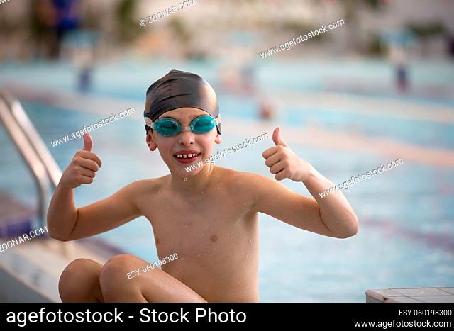 Boy in a swimming cap and swimming goggles in the pool. The child is engaged in the swimming section
