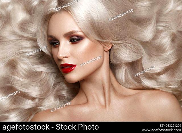 Beautiful blonde in a Hollywood manner with curls, natural makeup and red lips.. Beauty face and hair. Picture taken in the studio