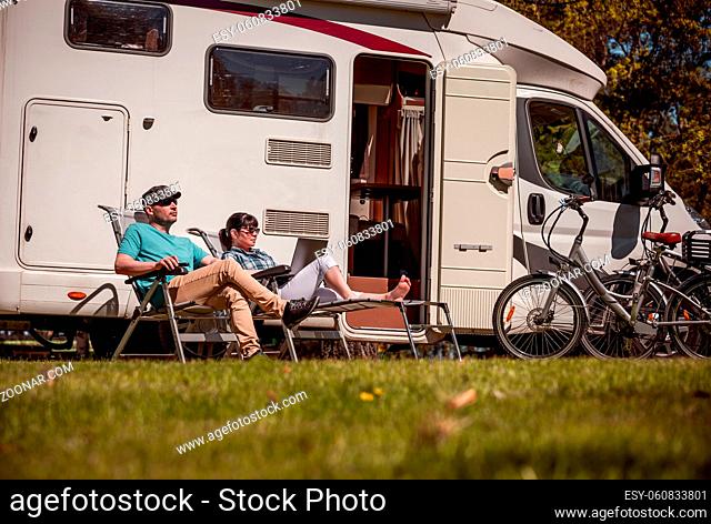 Woman with a man resting near motorhomes in nature. Family vacation travel, holiday trip in motorhome RV, Caravan car Vacation