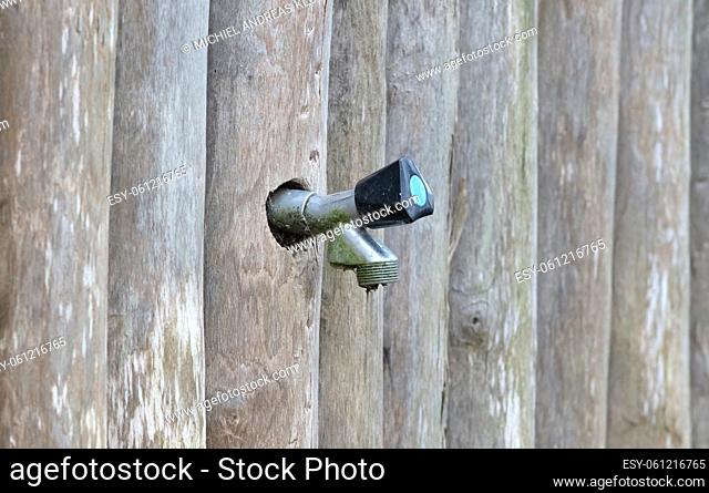 Outside watertap in a wooden wall, selective focus