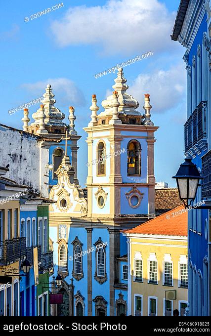 Old facades of colorful colonial-style houses, lanterns and windows and a tower of an old baroque church in Pelourinho, the famous historic center of Salvador