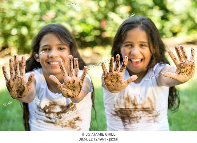 Mixed race girls covered in mud outdoors