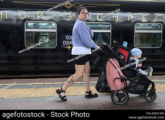 RUSSIA, MOSCOW - JULY 24, 2023: A woman pushes a pram past the Night Express train running between St Petersburg and Moscow, at Leningradsky railway station