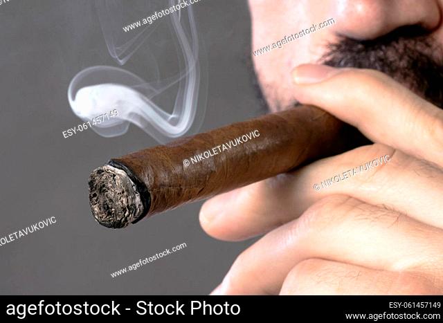 Close-up photo of smoking Cuban cigar, nicotine addiction