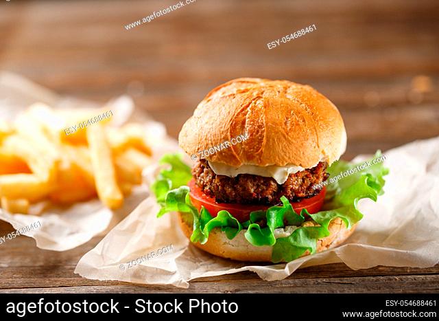 homemade burger and french fries on a wooden plate