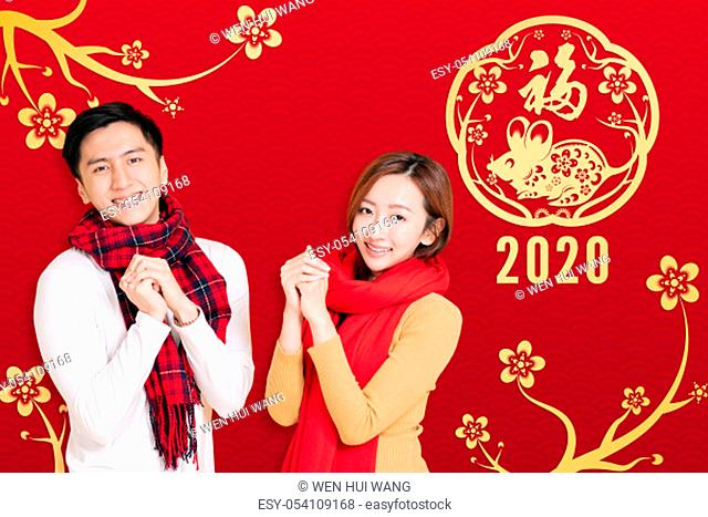 asian young couple celebrating for chinese new year. chinese text happy new year 2020