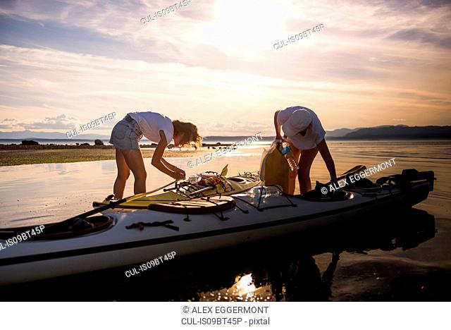 Two female kayakers preparing kayak, Quadra Island, Campbell River, Canada