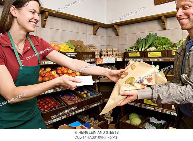 man paying shopkeeper for fruit