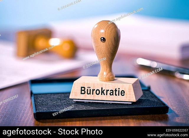 Ein Stempel mit der Aufschrift Bürokratie steht auf einem Schreibtisch