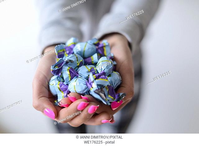 Selective focus-Girl with pink nail varnish hold wrapped chocholate sweets