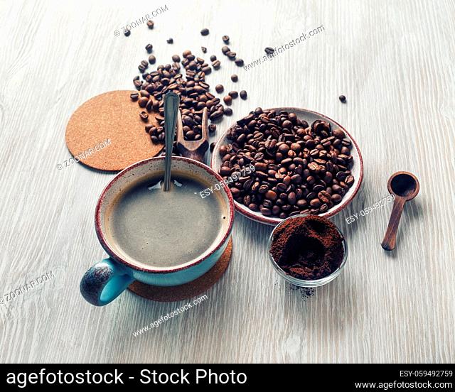 Fresh delicious coffee. Coffee cup, roasted coffee beans and ground powder on wooden background