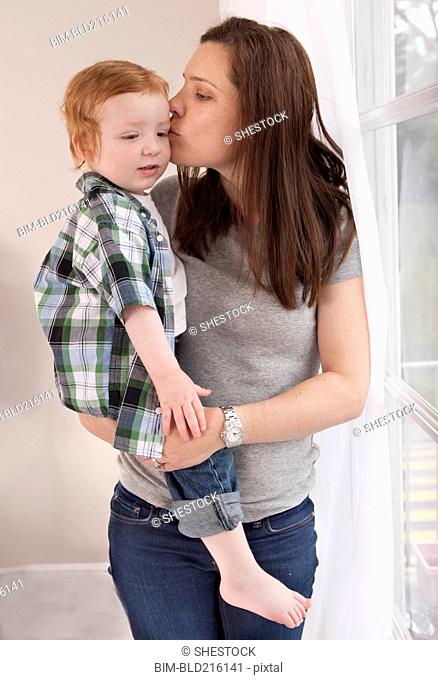 Mother kissing son near window
