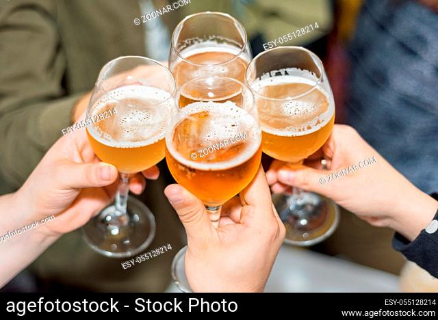 Group of friends drinking beer, toasting, at pub