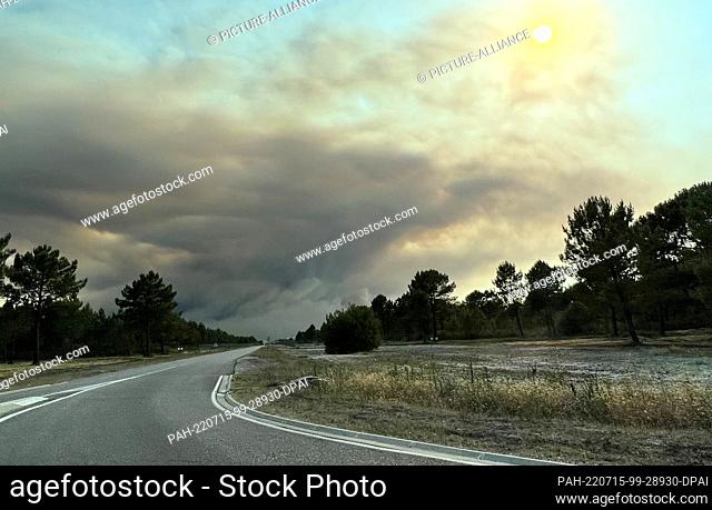 14 July 2022, France, La Teste-De-Buch: Dense clouds of smoke from a forest fire drift across a country road on the Atlantic coast about 60 southwest of...