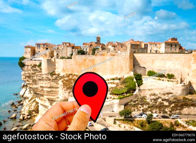 closeup of the hand of a caucasian man holding a red marker at the picturesque citadel of Bonifacio, in Corsica, France, on the top of a promontory