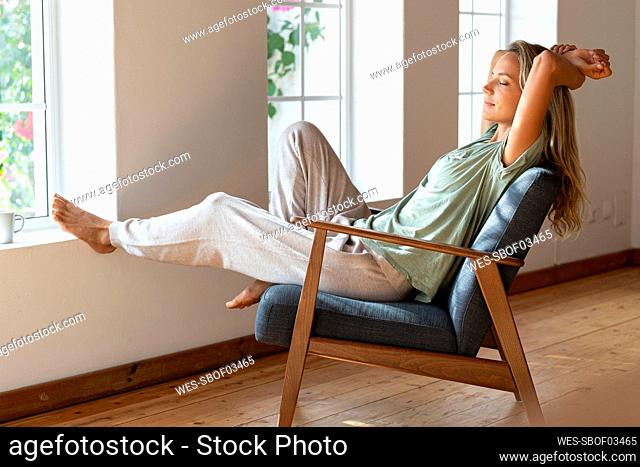 Woman with eyes closed resting on armchair at home