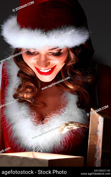 Christmas. happy girl in Santa hat opening glowing magic surprise gift box