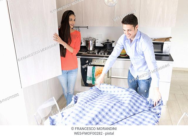 Smiling couple in kitchen preparing dining table