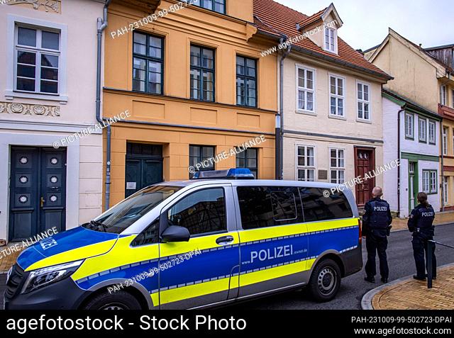 09 October 2023, Mecklenburg-Western Pomerania, Schwerin: Police officers stand with their patrol car in front of a building behind which the synagogue and the...