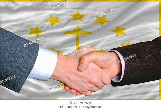 two businessmen shaking hands after good business investment agreement in front US state flag of rhode island