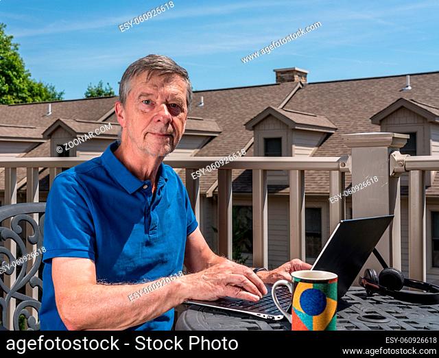 Senior caucasian man working from home during coronavirus epidemic using laptop and smiling at the camera