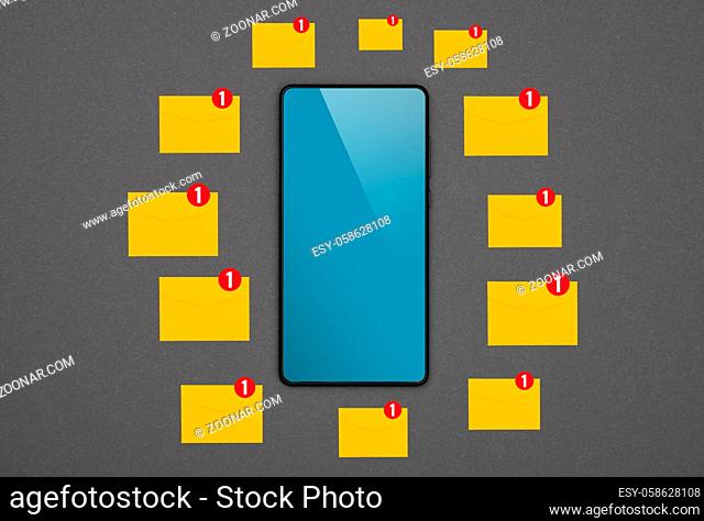 Close up one black smartphone with blank blue screen and many yellow envelopes of new messages over grey paper background, flat lay, directly above