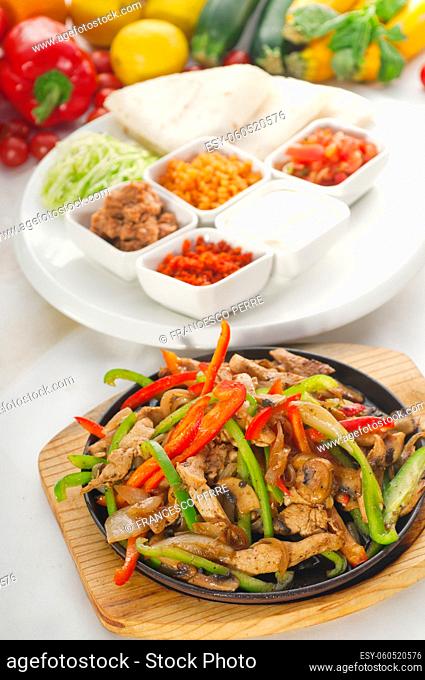 original fajita sizzling smoking hot served on iron plate and fresh vegetables on background , MORE DELICIOUS FOOD ON PORTFOLIO