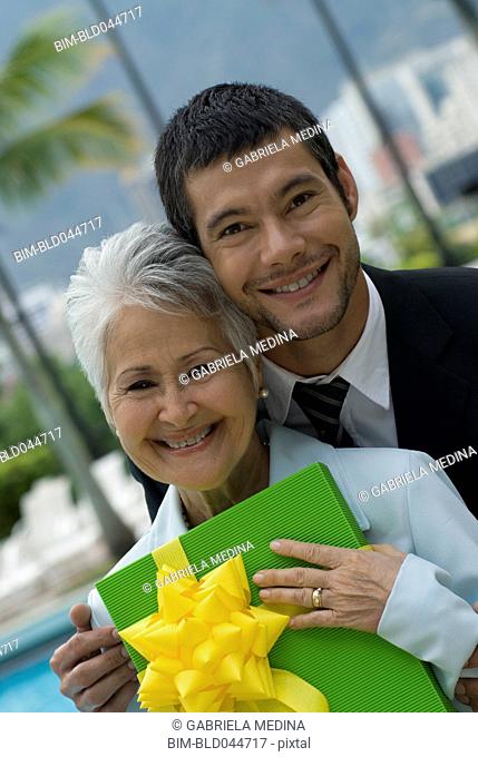 Hispanic man giving gift to mother