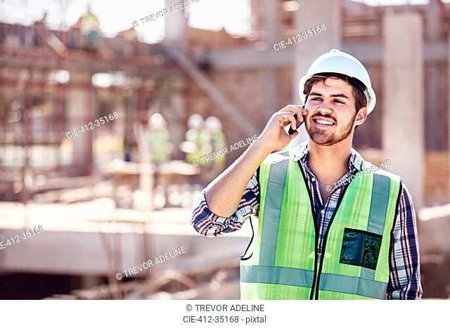 Construction worker talking on cell phone at sunny construction site