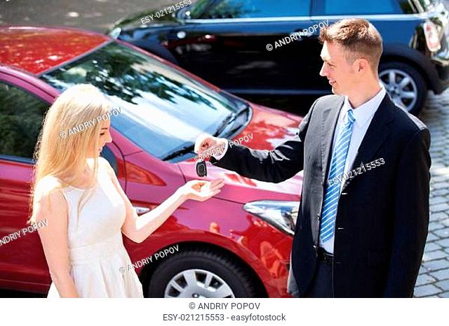 Salesman Handing Key To Woman By New Car