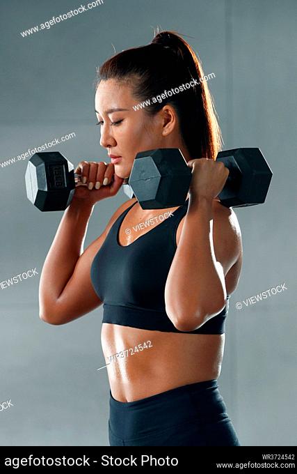 Young women at the gym dumbbell