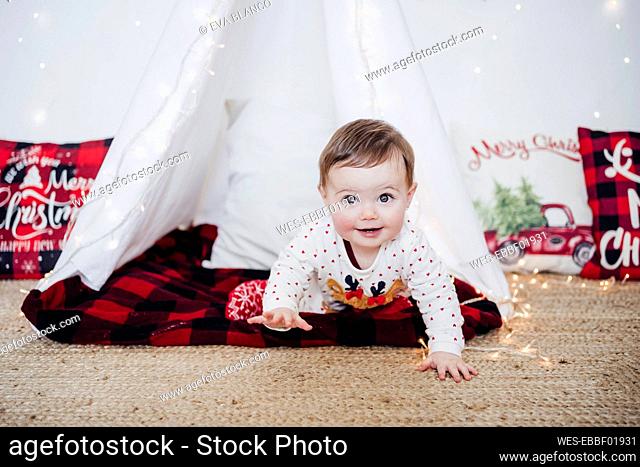 Baby girl crawling while playing in tent during Christmas at home