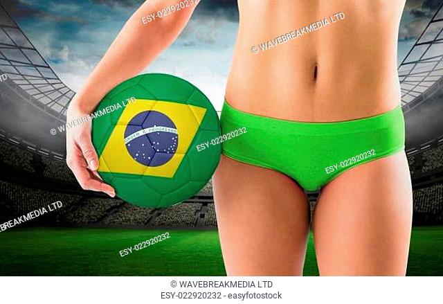 Composite image of fit girl in green bikini holding brazil football