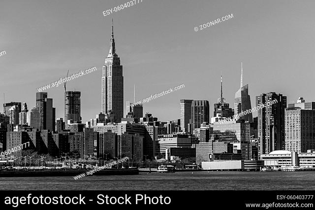 A black and white picture of the Empire State Building towering the nearby Manhattan buildings