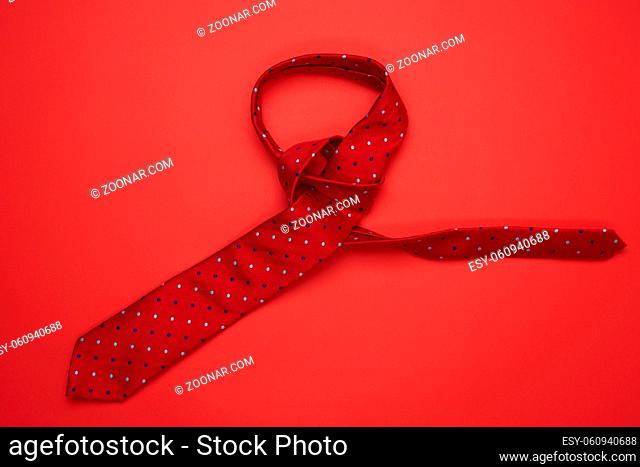 red silk tie on red background, top view