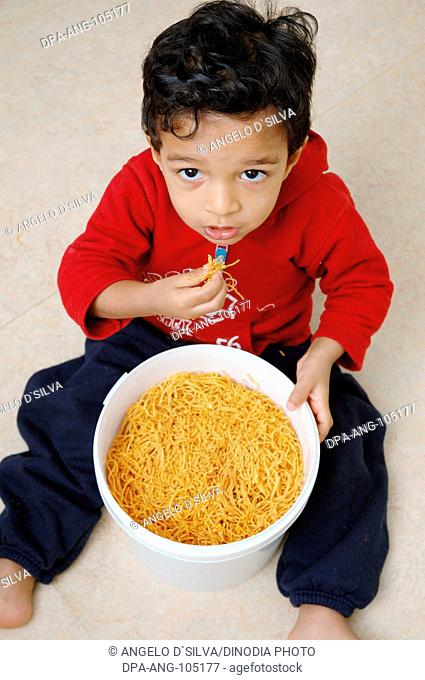 Small boy eating sev bhujia deep fried Indian snack MR # 468