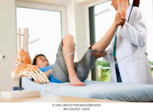 Orthopedic surgeon examining a teenage boy's injured leg