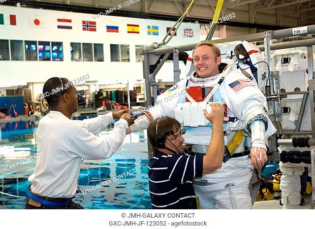 Astronaut Edward M. (Mike) Fincke, Expedition 18 commander, gets help donning a training version of the Extravehicular Mobility Unit (EMU) spacesuit prior to...