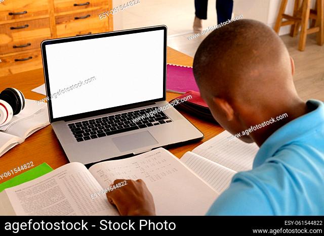African american male teenager learning with laptop with copy space