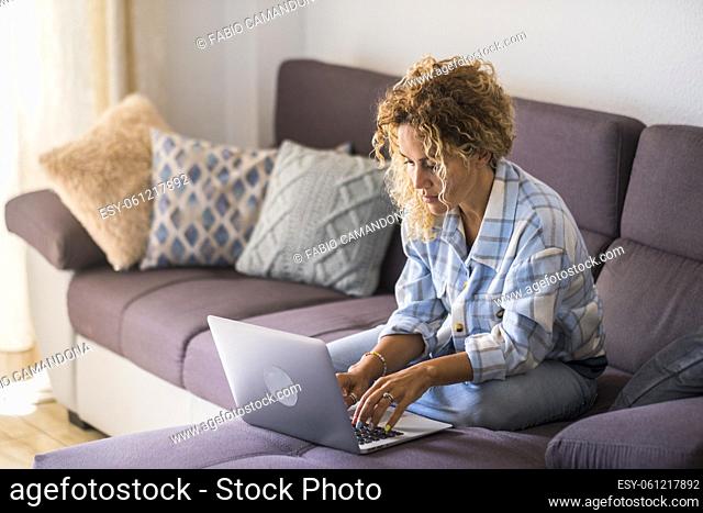 Modern woman laying on the couch and use laptop computer for work or surf the web - Adult female people enjoy internet technology in smart working and home...