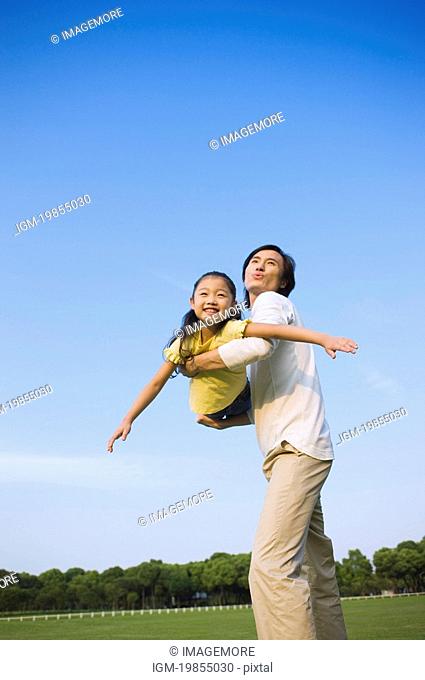 Young father holding daughter up in the mid-air