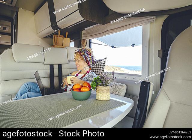 One woman using laptop inside a modern camper van. Van life and digital nomad remote worker female people lifestyle. Online job business in alternative caravan...