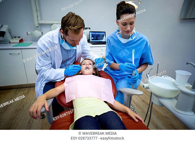Dentists examining a young patient with tools