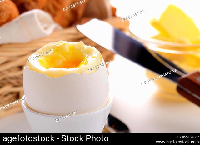 Breakfast of boiled egg croissant and butter over white