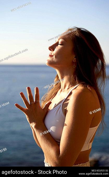Female athlete with eyes closed meditating at beach
