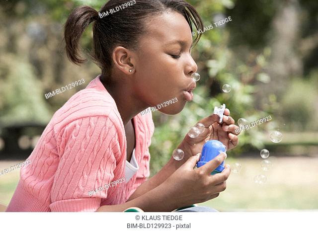 African American girl blowing bubbles outdoors