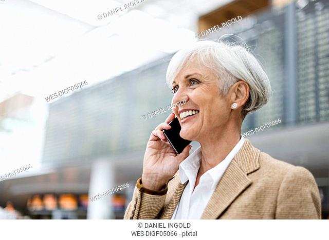 Smiling senior businesswoman on cell phone at the airport